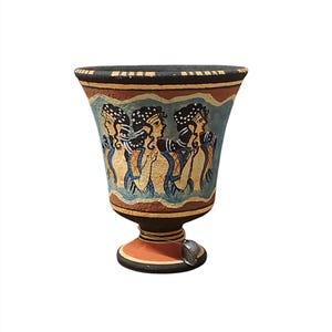 Può includere: Un piccolo vaso in ceramica dipinto a mano con un design nero, arancione e blu. Il vaso presenta tre donne di profilo, dipinte in uno stile greco tradizionale.
