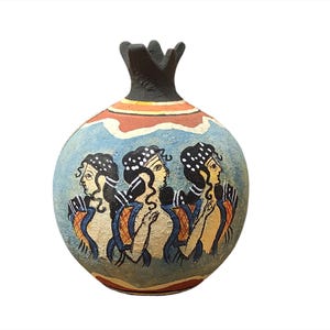 May include: A blue and orange ceramic pomegranate vase with three women painted on it. The women are wearing blue and white robes and have black hair.