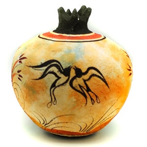 Può includere: Una piccola melagrana in ceramica dipinta a mano con un design nero e arancione. La melagrana è decorata con due uccelli in volo.