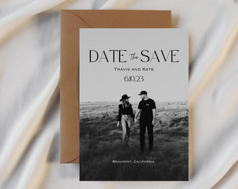 May include: Save the date card with a black and white photo of a couple in a field. The text reads "Date the Save" with the names "Travis and Kate" and the date "6.10.23". The location "Beaumont, California" is printed at the bottom.