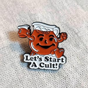 May include: A red and white enamel pin featuring a cartoon pitcher of orange juice with a smiling face and the text "Let's Start A Cult!"