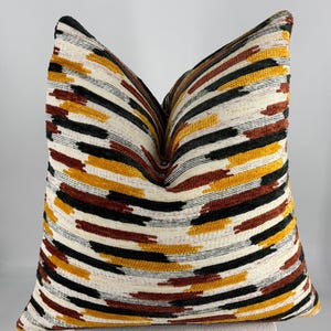 May include: A decorative throw pillow with a geometric pattern in shades of black, white, brown, and yellow.