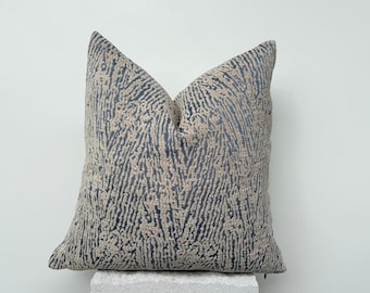 May include: A decorative throw pillow with a blue and beige abstract pattern. The pillow is made of a soft, textured fabric.