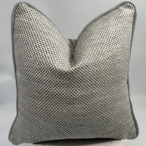 Federa per cuscino in tessuto a intreccio grigio e bianco con bordino in ciniglia grigia, tessuto spesso testurizzato in lino naturale, cuscino a quadri grigio e bianco.