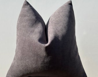 May include: A dark gray throw pillow with a textured fabric. The pillow is sitting on a white concrete block.
