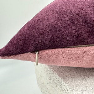 May include: A purple and pink pillow with a zipper closure. The pillow is made of a soft, velvety fabric.