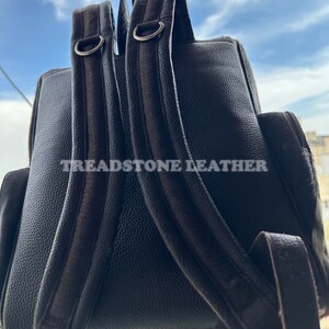 Pu&ograve; includere: Uno zaino in pelle nera con spallacci regolabili e una fibbia in metallo argentato. Lo zaino ha il testo "Treadstone Leather" stampato sul retro.