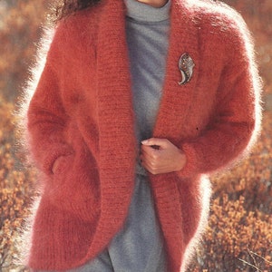 Könnte beinhalten: Ein weicher, flauschiger Cardigan in Korallenfarbe mit Schalkragen und Taschen. Der Cardigan ist vorne offen und hat eine lockere Passform.