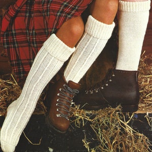 Puede incluir: Dos pares de calcetines blancos hasta la rodilla con textura acanalada. Los calcetines se llevan con botas de senderismo de cuero marrón.