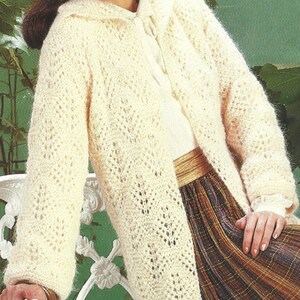 May include: A white crocheted cardigan with a delicate open stitch pattern. The cardigan has a shawl collar and long sleeves.