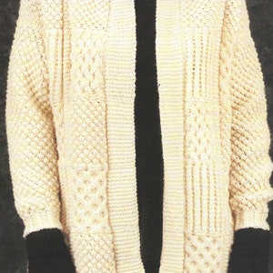 Könnte beinhalten: Ein cremefarbener Strickcardigan mit einem Zopfmuster und einer vorderen Öffnung. Der Cardigan hat lange Ärmel und einen gerippten Kragen.