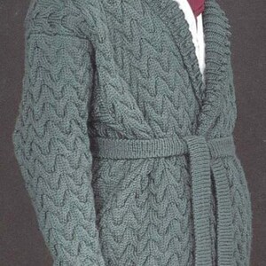 May include: A green knitted cardigan with a cable knit pattern and a self-tie belt. The cardigan has a shawl collar and a long, open front.
