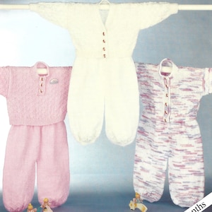 Puede incluir: Tres conjuntos de punto para bebé, uno blanco, uno rosa y otro con un patrón marmoleado rosa y morado. Cada conjunto incluye una parte superior y un pantalón.