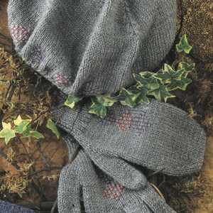 May include: A gray knitted hat and matching gloves with pink and purple embroidered flowers. The hat is a beret style and the gloves are fingerless.