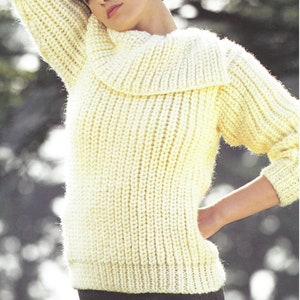 May include: A cream knitted jumper with a wide, folded turtleneck collar. The jumper has a ribbed texture.