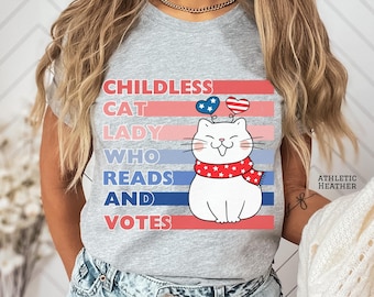 May include: Gray t-shirt with a white cat wearing a red and white scarf with stars. The cat has red and blue hearts above its head. The text on the shirt reads "Childless Cat Lady Who Reads And Votes".