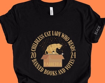 May include: Black t-shirt with a graphic of a cat sitting in a box with the text "Childless Cat Lady Who Reads 24 Banned Books and Votes 20".