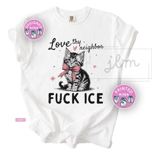 May include: White t-shirt featuring a black and white kitten wearing a pink bow tie. The shirt has the text "Love thy neighbor" and "FUCK ICE". Pink and black stars are also featured on the shirt.