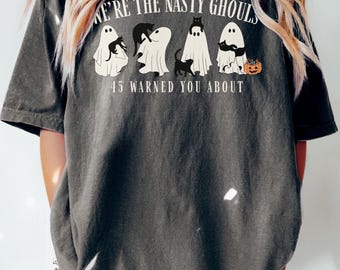 May include: Dark gray t-shirt with the text "WE'RE THE NASTY GHOULS" and "45 WARNED YOU ABOUT". The shirt features a graphic of four ghosts with black cats and a pumpkin, perfect for Halloween.
