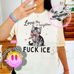 May include: Ivory-colored t-shirt featuring a black and white kitten with a pink bow, and the text "Love thy neighbor" above and "FUCK ICE" below. The shirt also has a "100% Cotton" graphic.