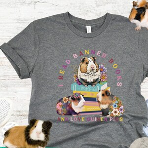 May include: Gray t-shirt with a graphic of three guinea pigs on a stack of books. The text around the guinea pigs reads "I read banned books and love guinea pigs".