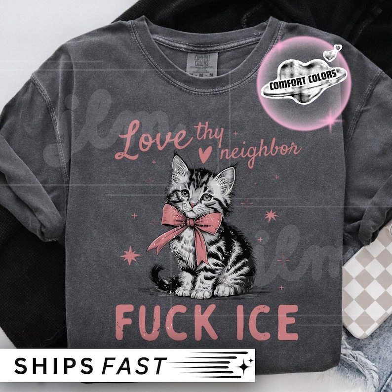 May include: Dark gray t-shirt with a graphic of a kitten wearing a pink bow tie. The text "Love thy neighbor" and "FUCK ICE" are printed in pink. The shirt also has the Comfort Colors logo.