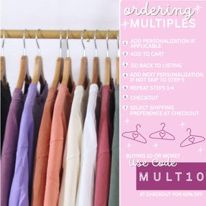 May include: A row of colorful t-shirts hanging on wooden hangers. The shirts are in various colors, including purple, orange, white, and green. Instructions for ordering multiples are displayed on the right side of the image.