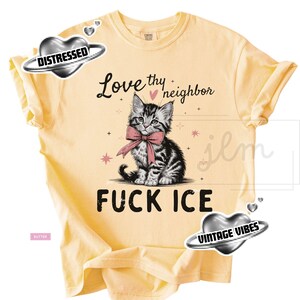 May include: Butter-colored t-shirt featuring a graphic of a kitten wearing a pink bow tie. The text "Love thy neighbor" and "FUCK ICE" are above and below the kitten illustration. The shirt has rolled-up sleeves.