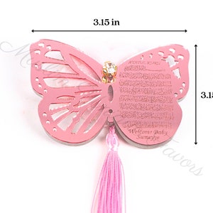 K&ouml;nnte beinhalten: Rosa Schmetterlingsf&ouml;rmiger Acryl-Anh&auml;nger mit einem rosa Quasten. Der Anh&auml;nger hat ein dekoratives Design und den Text "Welcome Baby Sumeyye". Der Anh&auml;nger misst 8 cm in der Breite und H&ouml;he.