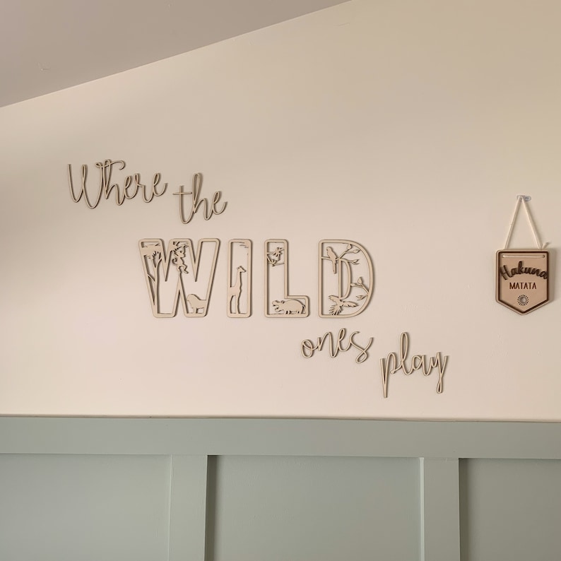 May include: Wooden wall decor with the words "Where the Wild Ones Play" and a sign that says "Hakuna Matata".