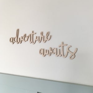 May include: Wooden wall decor with the words "adventure awaits" in a cursive font.