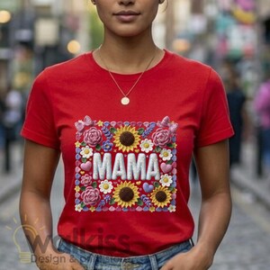 May include: Red t-shirt with a floral design that includes sunflowers, roses, and butterflies. The word "MAMA" is in white, embroidered-style letters in the center of the design. The shirt is short-sleeved and has a round neckline.