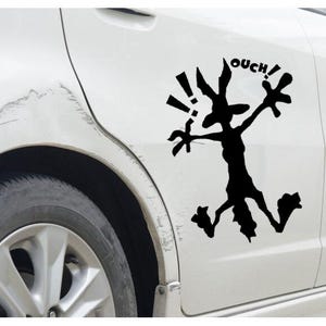 Może przedstawiać: Czarno-biała postać z kreskówki z napisem "OUCH!" nad nią. Postać biegnie z wyciągniętymi rękami i ma długi pysk. Kreskówka jest na białym samochodzie.