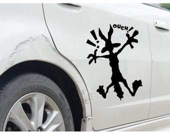 May include: A black and white cartoon character with the word "OUCH!" above it. The character is running with its arms outstretched and has a long snout. The cartoon is on a white car.