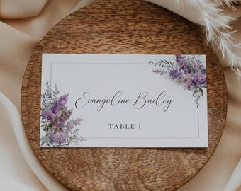 Puede incluir: Tarjeta de mesa de boda blanca con un diseño floral morado y el texto "Evangeline Bailey, Mesa 1".
