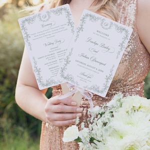 May include: Two wedding ceremony programs are held, featuring floral borders and elegant script. The programs display the wedding details, including the names of the couple, date, and venue. A bouquet of white flowers and a sequined dress are also visible.