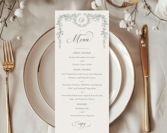 Puede incluir: Una tarjeta de menú de boda con un borde decorativo de hojas y flores verdes. El menú incluye un primer plato de crostini de bruschetta de tomate y una ensalada César clásica, un plato principal de solomillo de ternera con salsa, patatas asadas al horno y zanahorias glaseadas, o pollo al romero, arroz salvaje y pilaf de quinoa, y verduras de temporada, y un postre de pastel de boda y cuadrados de postre surtidos.