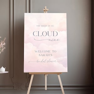 May include: A pink and white watercolor bridal shower sign with the text "The bride is on cloud nine. Welcome to Sarah's bridal shower."