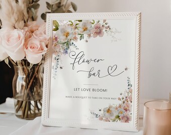 May include: A white sign with a floral design and the text "flower bar" and "LET LOVE BLOOM! MAKE A BOUQUET TO TAKE ON YOUR WAY!"