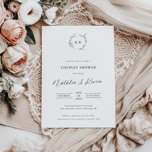 May include: A white wedding shower invitation with a floral wreath and the initials "NK" in the center. The text reads "Please join us for a Couples Shower honoring Natalie & Kevin Saturday, August 26, 4 o'clock 2024 Starling Estates Vineyard 363 Lakeshore Drive, Kelowna, BC RSVP to Jenna at 123-456-7890 Registered at Crate and Barrel and West Elm"