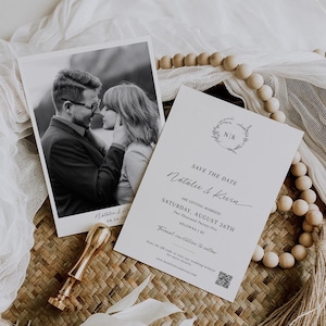 May include: A save the date card with a black and white photo of a couple in the top left corner. The card is white with black text and a floral wreath with the initials "N/K" in the center. The text reads "Save the Date, Natalie & Kevin, Are Getting Married! Saturday, August 26th, Two Thousand Twenty-Five, Kelowna, BC. Formal invitation to follow. Scan the QR code to visit our wedding website for more details. www.natalieandkevin.com"