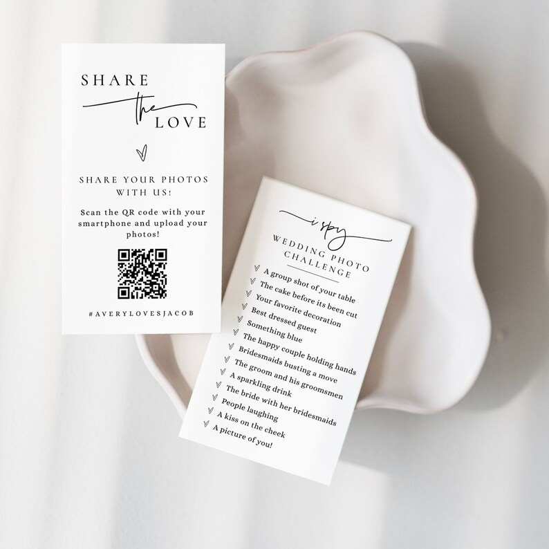 May include: Two white cards with black text. The first card says "Share the Love" and has a QR code with the text "#AveryLovesJacob". The second card says "I Spy Wedding Photo Challenge" and has a checklist of items to find in wedding photos.