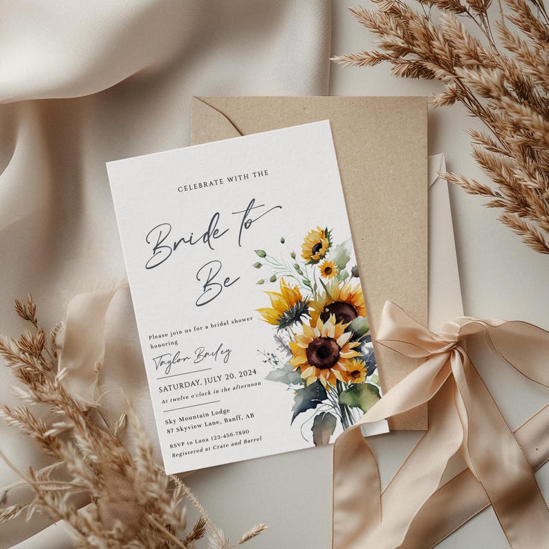 May include: A bridal shower invitation with the text "Bride to Be" in elegant script. The invitation features a watercolor bouquet of sunflowers and includes event details. The invitation is accompanied by a kraft paper envelope and a satin ribbon.