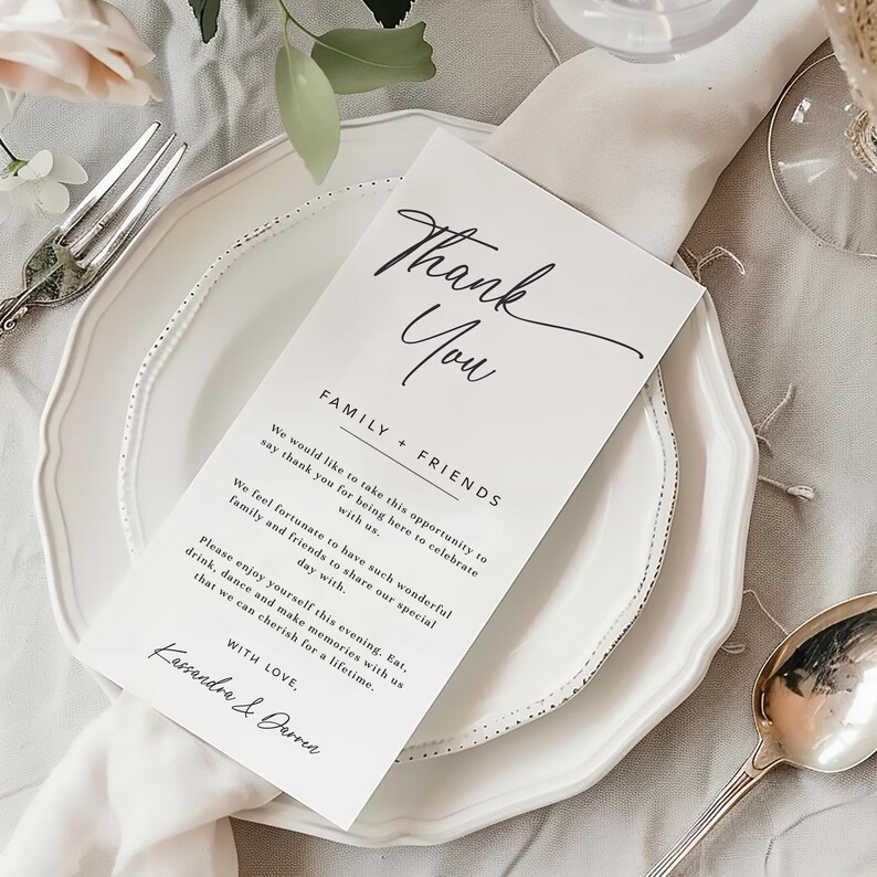 K&ouml;nnte beinhalten: Eine Hochzeitstafel mit einem wei&szlig;en Teller, Besteck und einer gefalteten Serviette. Auf dem Teller liegt eine Dankeskarte mit eleganter Schrift und gedrucktem Text. Die Karte lautet "Thank You" und enth&auml;lt eine Nachricht an Familie und Freunde.