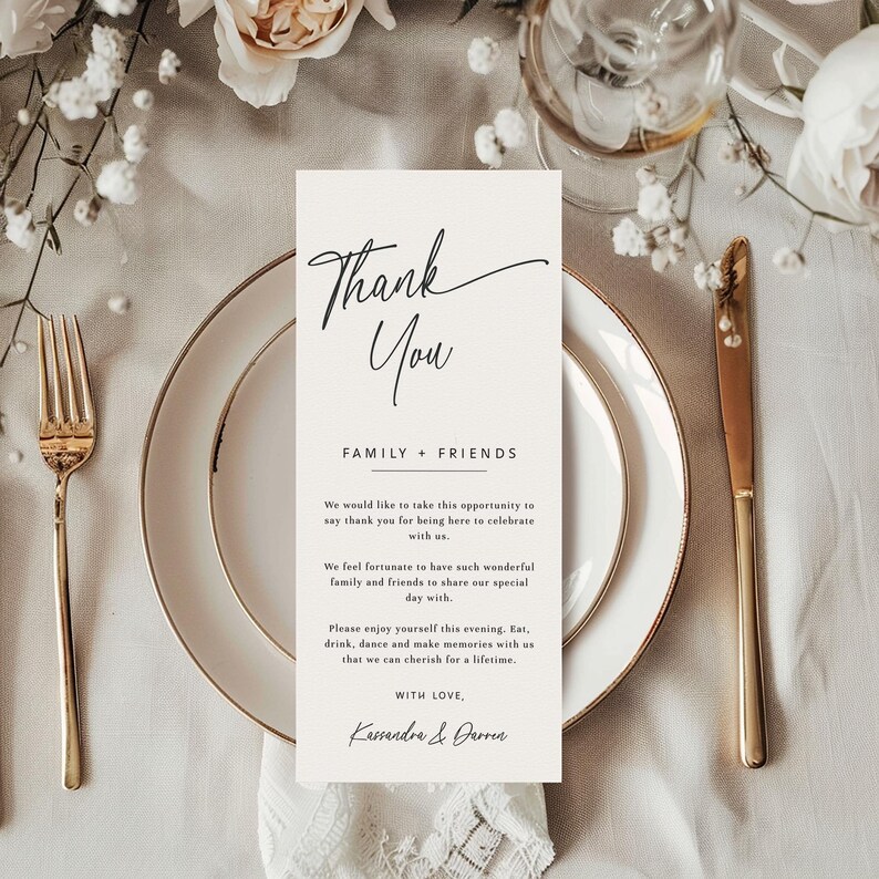 K&ouml;nnte beinhalten: Eine Hochzeitstafel mit einem goldger&auml;nderten Teller, einer goldenen Gabel und einem Messer. Eine cremefarbene Karte mit dem Schriftzug "Thank You" in eleganter Schrift ist auf dem Teller zentriert. Die Karte enth&auml;lt eine Nachricht an Familie und Freunde.