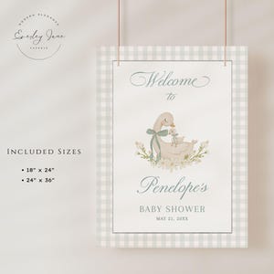 May include: A welcome sign for a baby shower with a light blue and white gingham background. The sign features a watercolor illustration of a mother goose and her gosling with a floral wreath. The text reads "Welcome to Penelope's Baby Shower May 21, 20XX".