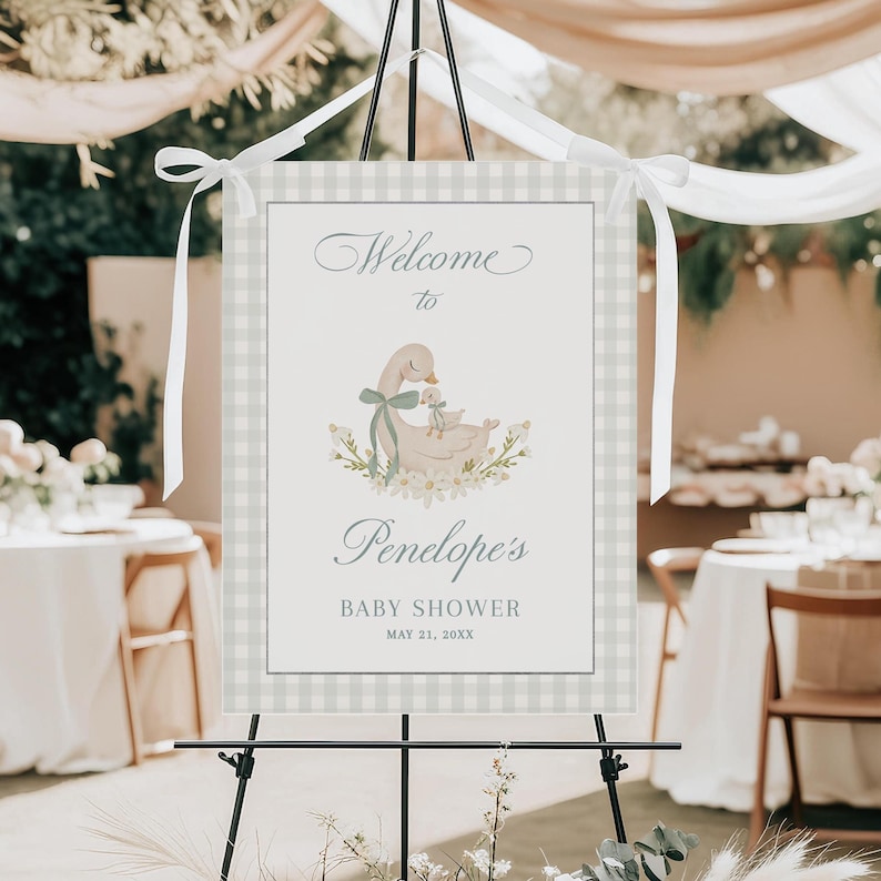 May include: Welcome to Penelope's Baby Shower sign with a light blue and white gingham background. A watercolor illustration of a mother duck and baby duck is featured in the center. The text reads "Welcome to Penelope's Baby Shower May 21, 20XX".