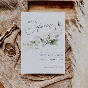 Peut inclure: Une carte d'invitation blanche avec des illustrations florales vertes et dor&eacute;es. Le texte indique "That's Amore" et comprend des d&eacute;tails pour une f&ecirc;te de mariage pour c&eacute;l&eacute;brer Sabrina & Marco. L'&eacute;v&eacute;nement est pr&eacute;vu pour le samedi 12 ao&ucirc;t 20XX &agrave; 16h00 &agrave; Bella Italia, 34 LaCosta Drive | Victoria, BC. Veuillez confirmer votre pr&eacute;sence aupr&egrave;s d'Amber au 123-456-7890.
