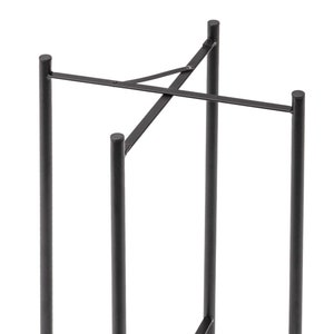 May include: Black metal stand with four legs and a cross-shaped design. The stand is made of sturdy metal and has a simple, modern design.