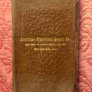 May include: A brown leather-bound book with gold lettering on the cover that reads "American Electrical Supply Co. 660-668 Washington Blvd. Chicago, Ill."